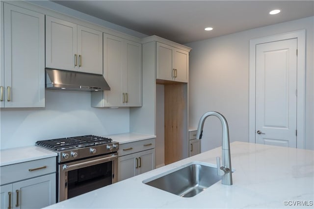 kitchen featuring gray cabinets, light stone counters, sink, and high end stainless steel range oven