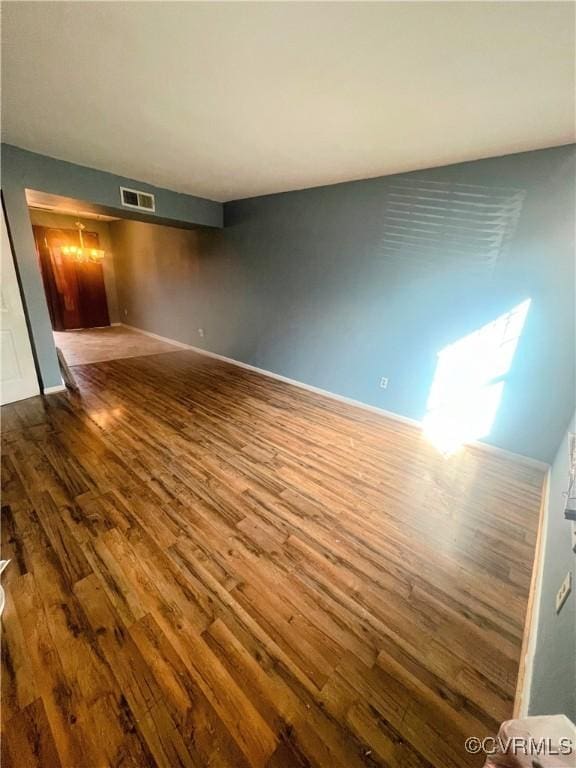 spare room with wood-type flooring and a notable chandelier