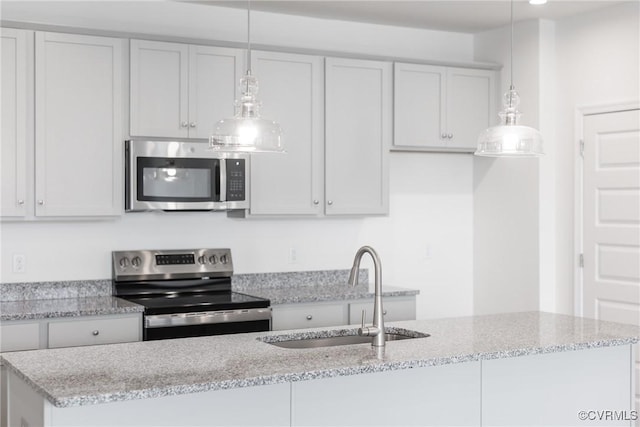 kitchen with decorative light fixtures, light stone counters, sink, and appliances with stainless steel finishes