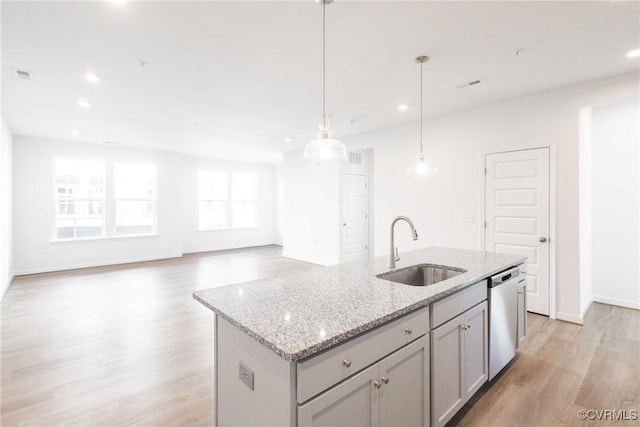 kitchen featuring dishwasher, a kitchen island with sink, hanging light fixtures, sink, and gray cabinets