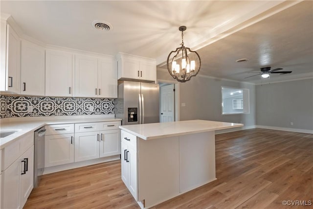 kitchen with decorative light fixtures, white cabinetry, stainless steel appliances, and light hardwood / wood-style flooring