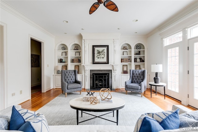 living room featuring built in shelves, light hardwood / wood-style floors, and a wealth of natural light