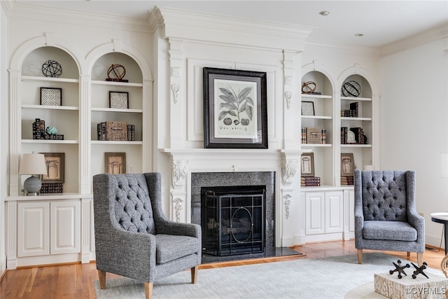 sitting room with built in features, light hardwood / wood-style floors, and ornamental molding