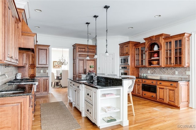 kitchen featuring stainless steel appliances, a kitchen breakfast bar, dark stone countertops, decorative light fixtures, and white cabinets