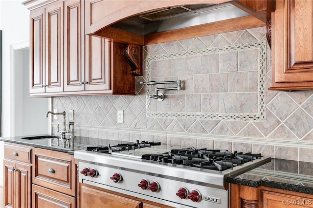 kitchen with tasteful backsplash, stainless steel gas cooktop, dark stone countertops, and sink