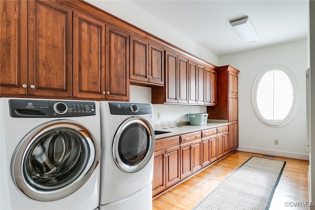 laundry room with washer and dryer, light hardwood / wood-style floors, and cabinets