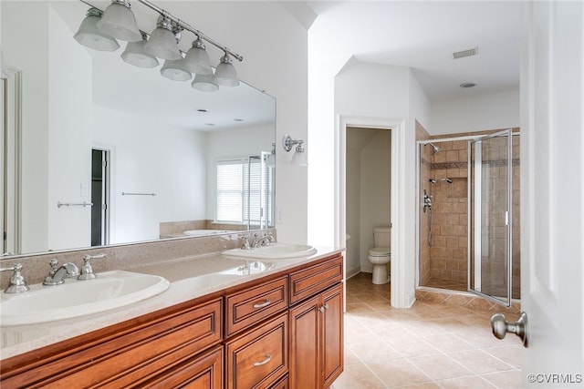 bathroom featuring tile patterned flooring, vanity, toilet, and a shower with door