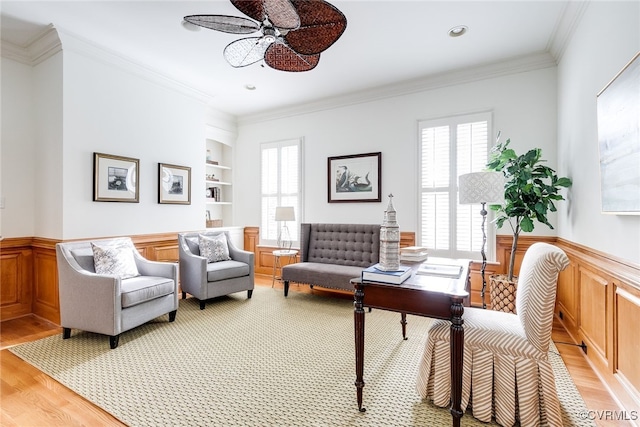 living room with crown molding, built in features, ceiling fan, and light hardwood / wood-style floors