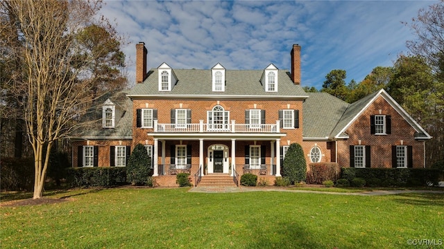 colonial-style house featuring covered porch and a front yard