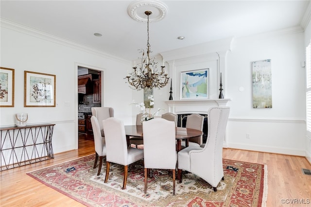 dining space with crown molding, light hardwood / wood-style flooring, and a chandelier