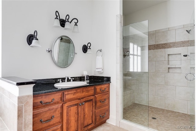 bathroom featuring tile patterned flooring, vanity, and tiled shower