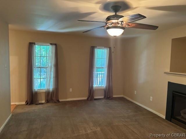 unfurnished living room featuring ceiling fan and dark colored carpet