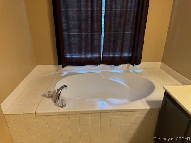 bathroom with vanity and tiled bath