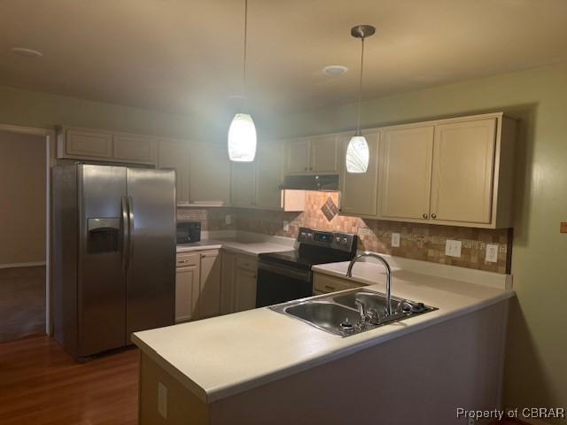 kitchen featuring sink, dark wood-type flooring, hanging light fixtures, backsplash, and black appliances