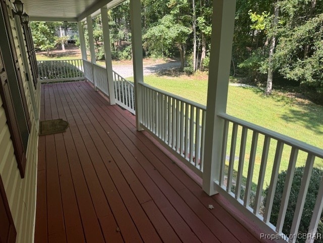 wooden terrace featuring a porch and a yard