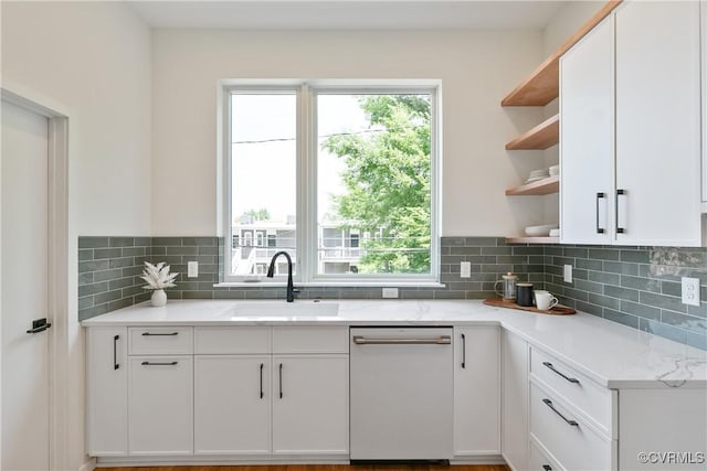 kitchen featuring white cabinets, light stone counters, dishwasher, and sink