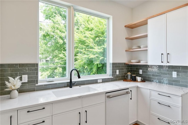 kitchen featuring light stone countertops, white cabinetry, a healthy amount of sunlight, and sink