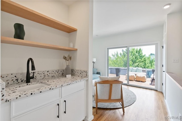 interior space featuring light wood-type flooring, light stone counters, white cabinetry, and sink