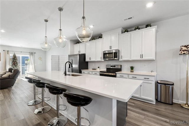 kitchen featuring hanging light fixtures, white cabinets, and stainless steel appliances