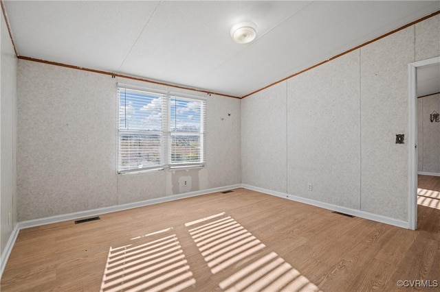 empty room featuring light wood-type flooring and ornamental molding