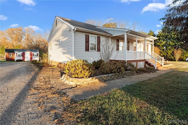 view of side of property with an outbuilding, a porch, and a lawn