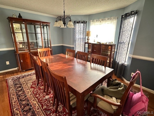 dining area featuring a chandelier, crown molding, dark wood-type flooring, and a textured ceiling