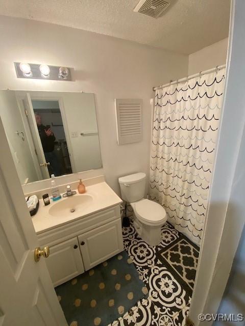 bathroom with vanity, toilet, a textured ceiling, and walk in shower