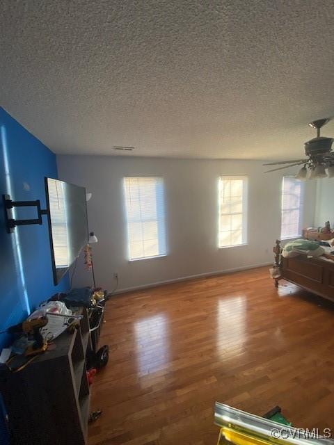 interior space featuring plenty of natural light, ceiling fan, wood-type flooring, and a textured ceiling