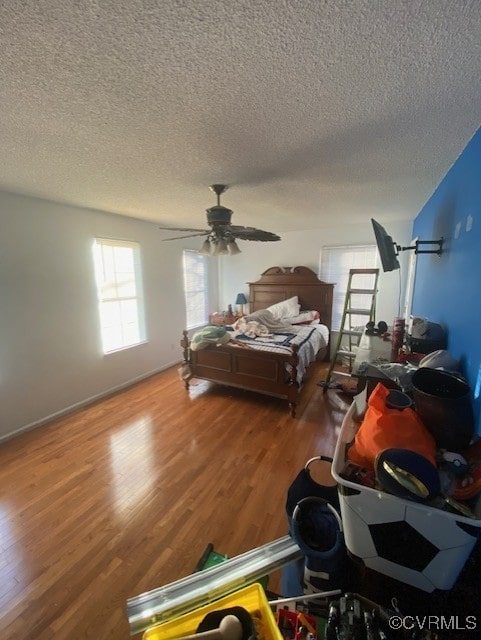 bedroom featuring hardwood / wood-style floors, ceiling fan, and a textured ceiling