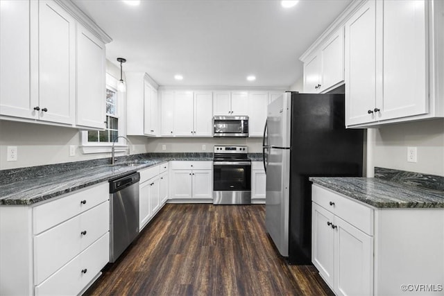 kitchen with appliances with stainless steel finishes, sink, pendant lighting, white cabinets, and dark hardwood / wood-style floors