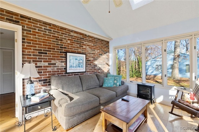 sunroom featuring a wood stove, ceiling fan, and vaulted ceiling with skylight