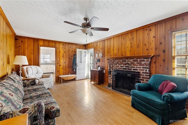 living room featuring a textured ceiling, light wood-type flooring, crown molding, and wood walls