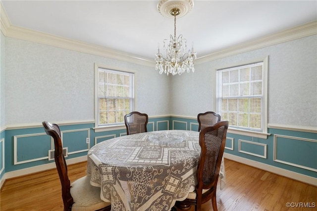 dining space with crown molding, plenty of natural light, wood-type flooring, and a notable chandelier