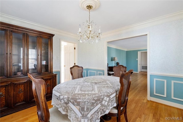 dining area featuring a notable chandelier, light hardwood / wood-style floors, and ornamental molding