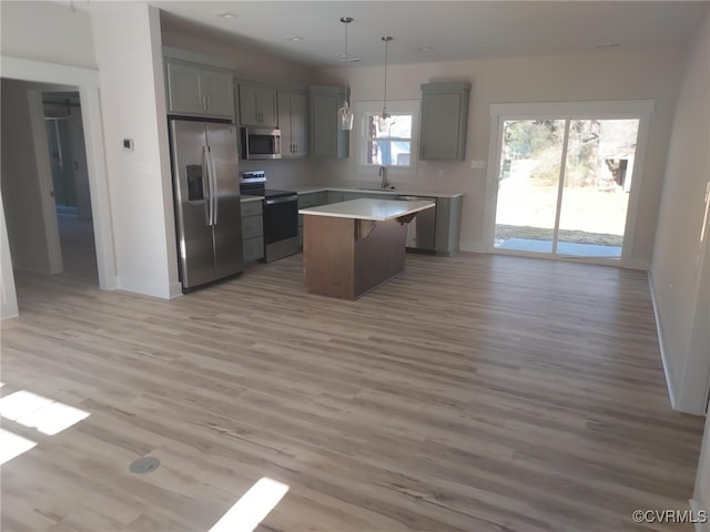 kitchen featuring pendant lighting, sink, appliances with stainless steel finishes, gray cabinetry, and a center island