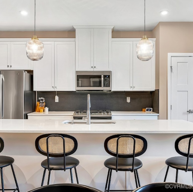 kitchen featuring a center island with sink, decorative backsplash, pendant lighting, and stainless steel appliances