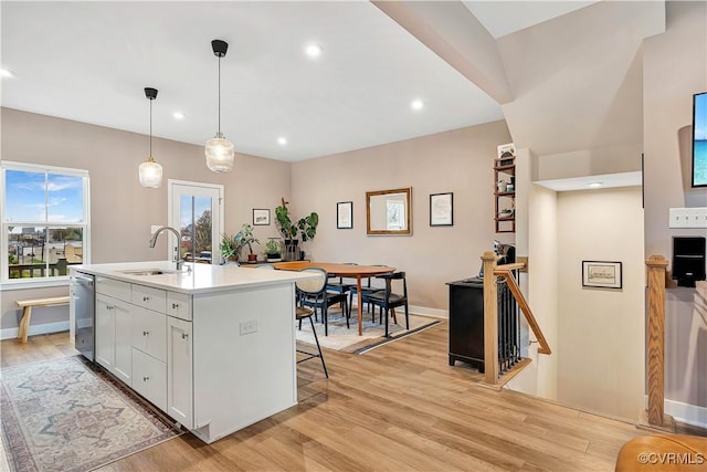 kitchen with dishwasher, sink, light hardwood / wood-style floors, a center island with sink, and white cabinets