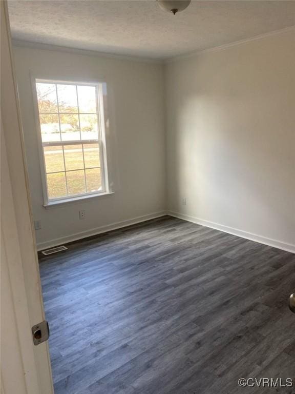 spare room with a textured ceiling, dark hardwood / wood-style floors, and crown molding