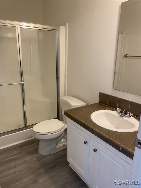 bathroom with toilet, vanity, a shower with shower door, and hardwood / wood-style flooring