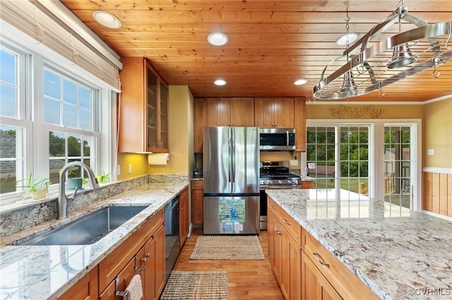 kitchen with light stone counters, sink, stainless steel appliances, and light hardwood / wood-style floors