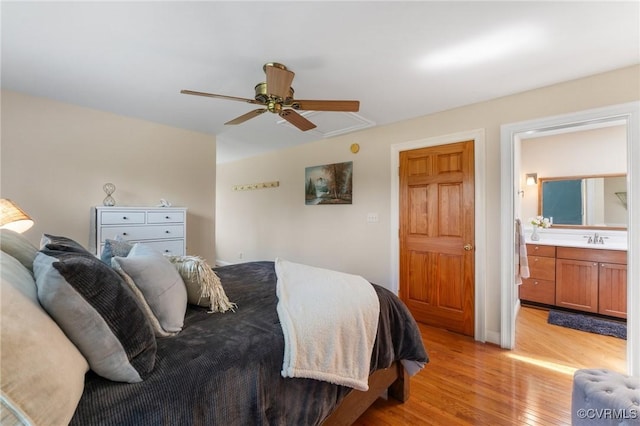 bedroom featuring connected bathroom, light wood-type flooring, ceiling fan, and sink