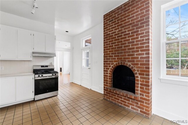 kitchen with white cabinetry, stainless steel range with gas cooktop, ventilation hood, backsplash, and light tile patterned flooring