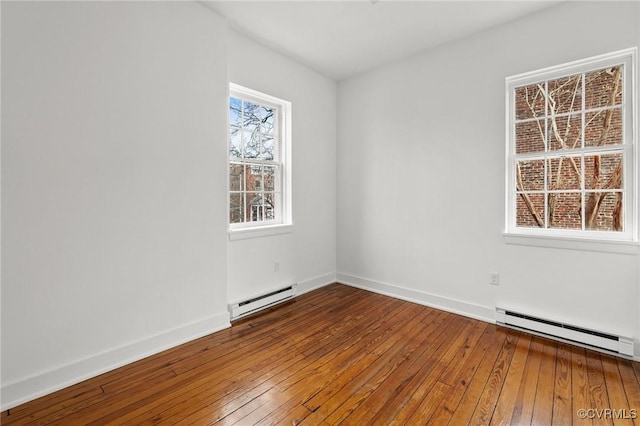 empty room featuring hardwood / wood-style flooring and a baseboard heating unit