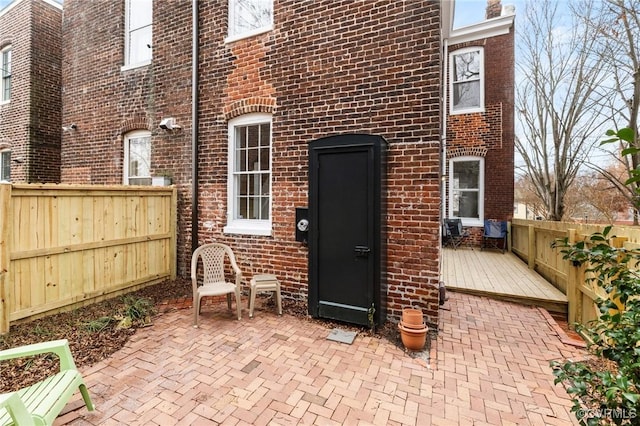 view of exterior entry featuring a deck and a patio