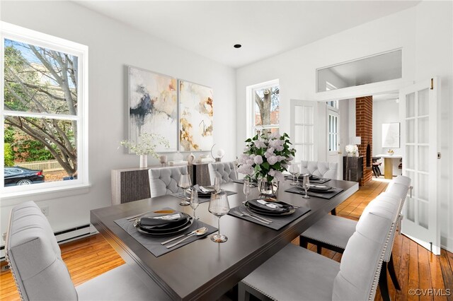 dining area with hardwood / wood-style flooring, french doors, a wealth of natural light, and a baseboard heating unit