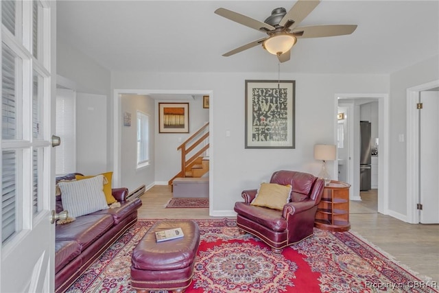 living room with ceiling fan, a baseboard radiator, and light hardwood / wood-style flooring