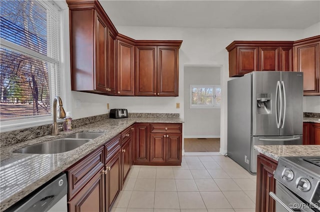 kitchen with light stone countertops, sink, light tile patterned floors, and appliances with stainless steel finishes