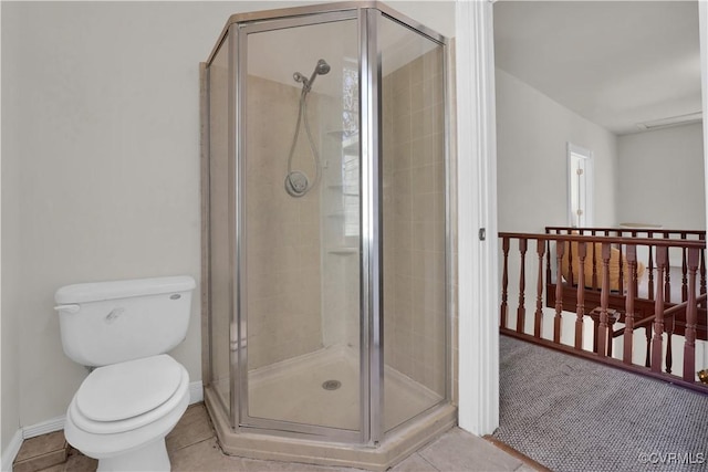 bathroom featuring tile patterned flooring, toilet, and a shower with shower door