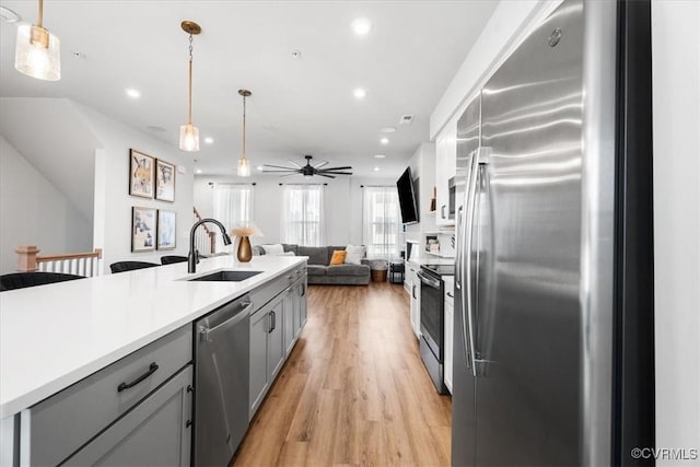 kitchen with stainless steel appliances, hanging light fixtures, sink, and gray cabinets