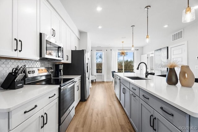 kitchen featuring sink, gray cabinets, stainless steel appliances, white cabinets, and decorative light fixtures